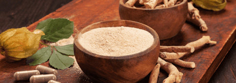 Ashwagandha powder in a wooden bowl with dried roots.
