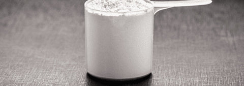 Creatine powder measured in a scoop on a dark surface