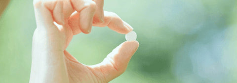 Person holding vitamin B capsules and tablets in hand.